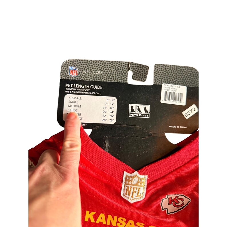 May include: A red Kansas City Chiefs pet jersey with the NFL logo and team logo. The jersey has a size guide for pet length, ranging from X-Small (6-9 inches) to Large (20-24 inches).