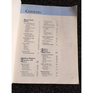Op de afbeelding: Pagina uit een open boek met een inhoudsopgave met de titel "CONTENTS". De pagina bevat onderwerpen over Visual Studio .NET, het bouwen van multitier-programma's en Windows-database-applicaties. Zwarte tekst op een witte achtergrond.