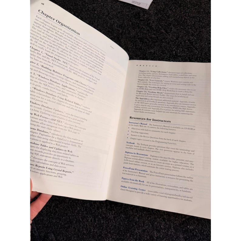 Op de afbeelding: Open boek met tekst op de pagina's. De linkerpagina heeft de titel "Chapter Organization" en bevat hoofdstuktitels. De rechterpagina bevat bronnen voor instructeurs. Het boek ligt open op een donkere ondergrond.