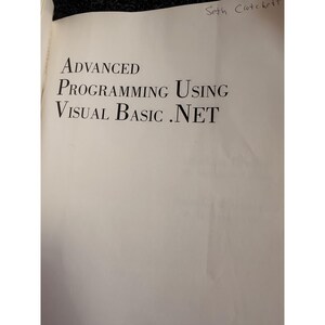 Op de afbeelding: Open boek met de titel "ADVANCED PROGRAMMING USING VISUAL BASIC .NET" in grote, zwarte letters. De naam van de auteur, Seth Crotchett, is met de hand geschreven rechtsboven. De pagina's zijn gebroken wit.