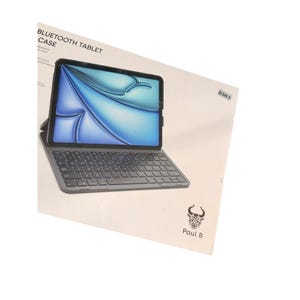 Puede incluir: Una funda para tableta Bluetooth con teclado integrado. La pantalla de la tableta muestra un diseño abstracto azul y blanco. El texto "Bluetooth Tablet Case" está impreso en la parte superior izquierda. La marca "Paul B" está impresa en la parte inferior derecha.