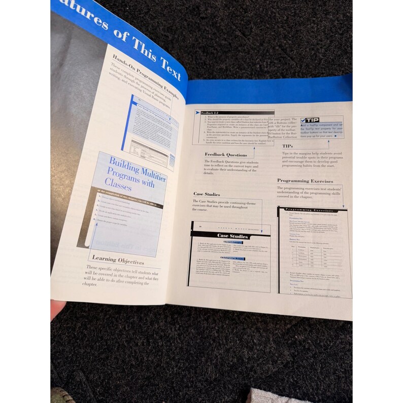 Op de afbeelding: Open boek met blauwe accenten, met tekst en diagrammen. Secties zijn onder meer "Building Multitier Programs with Classes", "Feedback Questions" en "Case Studies". Bevat ook "Learning Objectives" en "Programming Exercises".