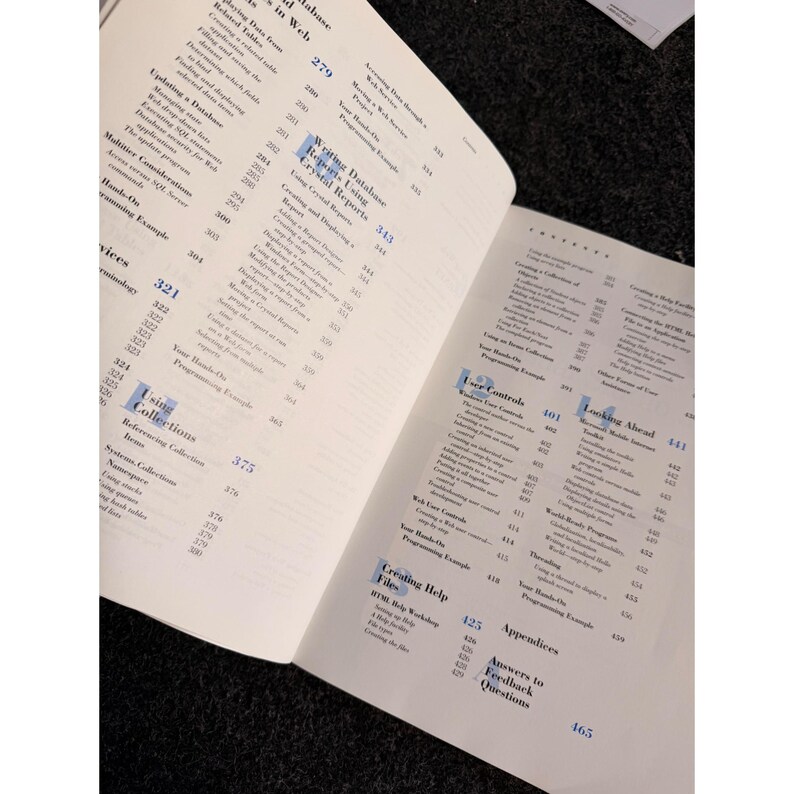 Op de afbeelding: Open boek met witte pagina's vol zwarte tekst en cijfers. Het boek is opengeslagen op een spread met de titels "Using Collections" en "User Controls". Paginanummers zijn zichtbaar.