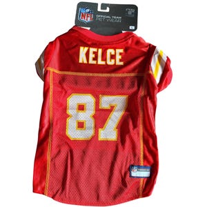 May include: Red mesh pet jersey with the name "KELCE" and the number "87" in yellow. The jersey has yellow and white accents on the sleeves and collar. The NFL Official Team Pet Wear tag is attached.