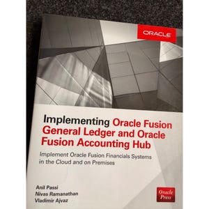 May include: A book titled "Implementing Oracle Fusion General Ledger and Oracle Fusion Accounting Hub." The cover features a geometric architectural design in shades of gray and a red "ORACLE" logo. The book is published by Oracle Press.