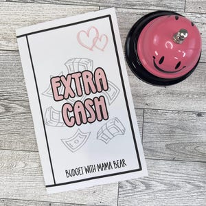 May include: A white printable budget planner with the text "EXTRA CASH" in pink letters and the text "BUDGET WITH MAMA BEAR" at the bottom. The planner features a design of money bills and hearts.