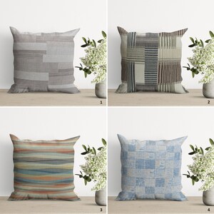 May include: Four different throw pillow designs with geometric patterns. The pillows are all square and have a neutral color palette. The first pillow is a light gray with brown and white stripes. The second pillow is a light beige with brown, white, and blue stripes. The third pillow is a light orange with blue and white stripes. The fourth pillow is a light blue with white and gray stripes.