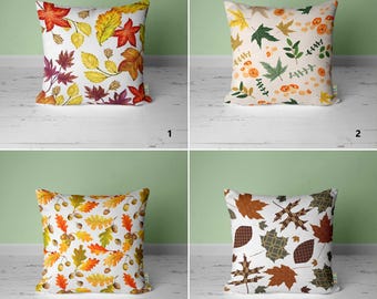 May include: Four different pillow designs featuring autumn leaves in various colors and patterns. The pillows are all white with a variety of fall foliage designs, including red, orange, yellow, and brown leaves.