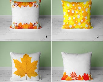 May include: Four different throw pillow designs featuring autumnal themes. The first pillow has a white background with a border of orange pumpkins and green leaves. The second pillow has a yellow background with white and orange abstract leaves. The third pillow has a white background with a single large orange and yellow leaf. The fourth pillow has a white background with a bottom border of orange and red leaves.