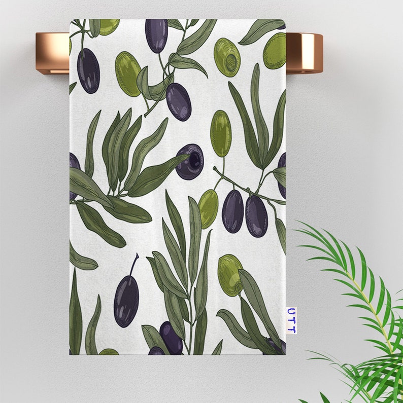 White kitchen towel with a black and green olive branch pattern.
