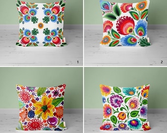 May include: Four decorative pillow covers with colorful floral patterns inspired by traditional Polish folk art. The pillows feature a white background with vibrant red, blue, green, yellow, and orange flowers.