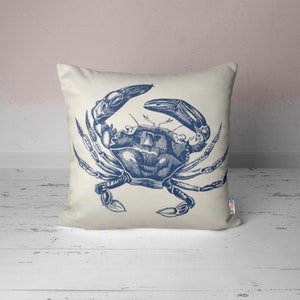 A white pillow with a blue illustration of a crab on it.