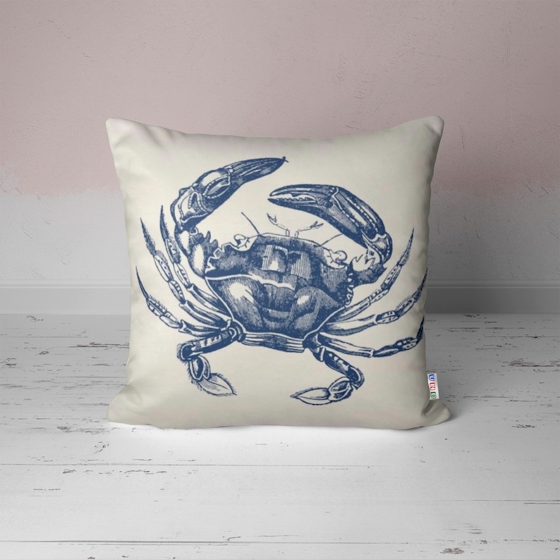 A white pillow with a blue illustration of a crab on it.