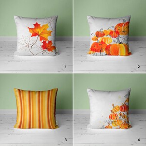 May include: Four different pillow designs featuring autumnal themes. The first pillow has a white background with orange and red maple leaves. The second pillow has a white background with orange and red pumpkins. The third pillow has a yellow and orange striped pattern. The fourth pillow has a white background with orange and red pumpkins.