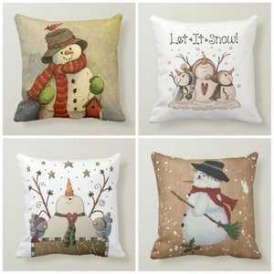 May include: Four different pillow designs featuring snowmen. The first pillow has a snowman with a red scarf and a bird on its hat. The second pillow has three snowmen with the text "Let It Snow!" The third pillow has a snowman with a red scarf and two birds. The fourth pillow has a snowman with a red scarf and a broom.