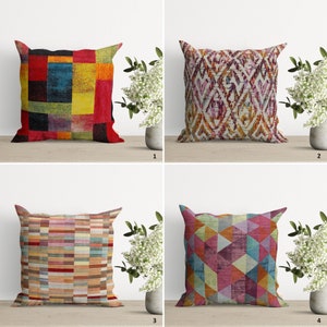 Pode incluir: Quatro almofadas decorativas com diferentes padrões geométricos. As almofadas são todas quadradas e têm uma variedade de cores, incluindo vermelho, amarelo, azul, verde e marrom. As almofadas estão dispostas em um padrão de grade em uma superfície de madeira.