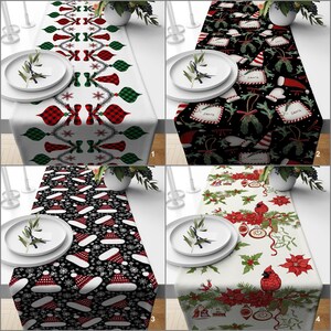 Könnte beinhalten: Vier Tischläufer zum Thema Weihnachten mit verschiedenen Designs. Einer zeigt rote und grüne Ornamente auf weißem Hintergrund. Ein anderer hat einen schwarzen Hintergrund mit Weihnachtsmützen und Schneeflocken. Der dritte hat einen schwarzen Hintergrund mit Santa-Tags und Ornamenten. Der letzte hat einen weißen Hintergrund mit roten Weihnachtssternen und einem Kardinal.