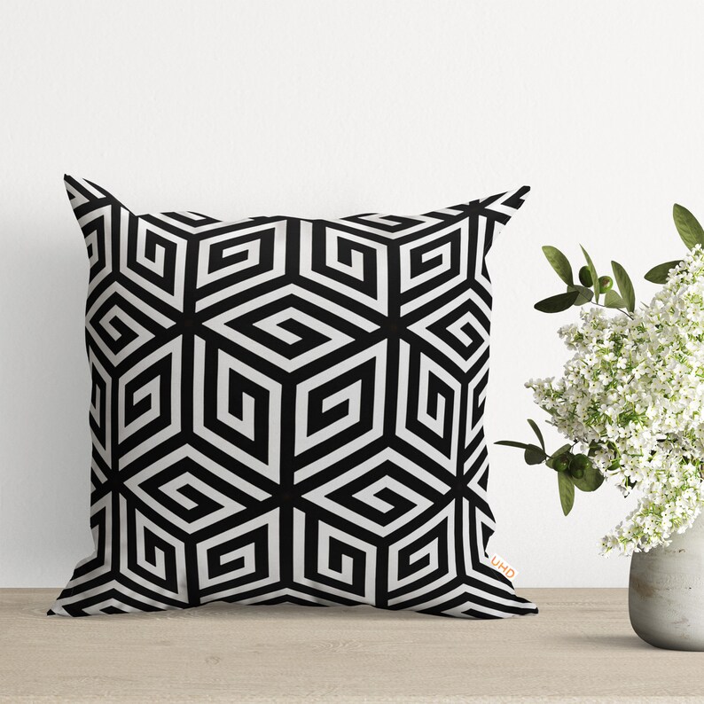 Black and white geometric patterned throw pillow with a white background and black geometric shapes.