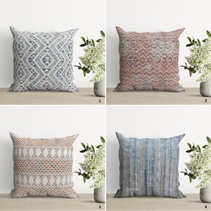 May include: Four decorative throw pillows with geometric patterns. The pillows are in shades of blue, red, white, and multi-colored. The pillows are arranged in a grid pattern on a wooden surface.