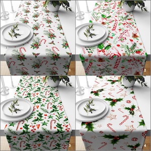 Könnte beinhalten: Vier weihnachtliche Tischläufer mit weißen Hintergründen, jeder mit einem anderen festlichen Muster. Designs umfassen Zuckerstangen, Stechpalmen, Beeren und Sterne. Gezeigt auf einem Tisch mit Tellern und Grün, ideal für ein Weihnachtsessen.