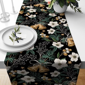 Black table runner with a repeating pattern of white flowers, gold bells, and green leaves.