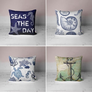 May include: Four decorative throw pillows with nautical themes. The pillows feature a blue and white seashell design, a blue and white anchor design, a blue and white octopus and turtle design, and a blue pillow with the text "Seas the Day" and a seahorse.