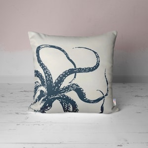 A white throw pillow with a navy blue octopus illustration. The octopus has many tentacles with suckers.
