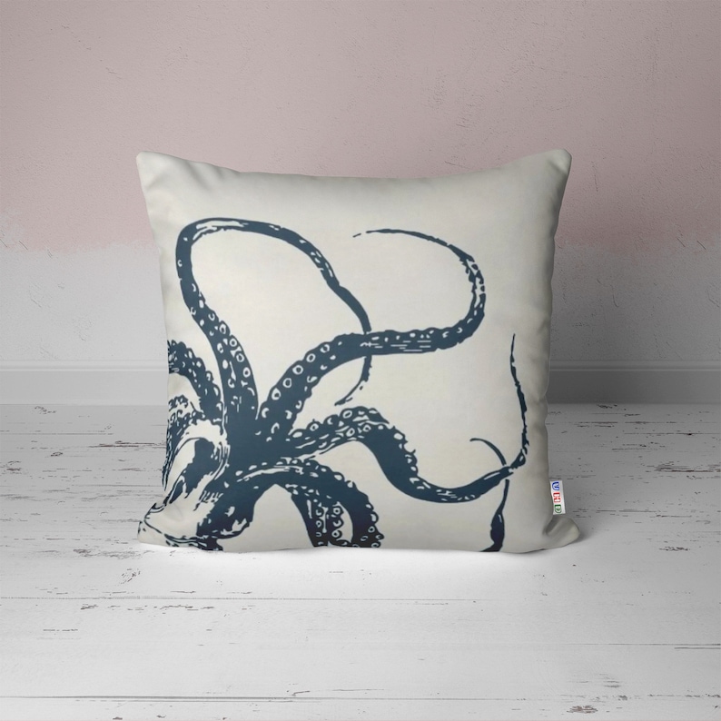 A white throw pillow with a navy blue octopus illustration. The octopus has many tentacles with suckers.