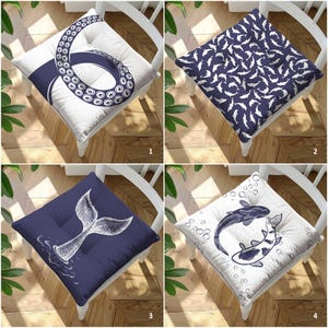 May include: A set of four square seat cushions featuring nautical designs. One cushion has a white background with a dark blue octopus tentacle, one has a dark blue background with white dolphins, one has a dark blue background with a white whale tail, and one has a white background with dark blue koi fish and bubbles.