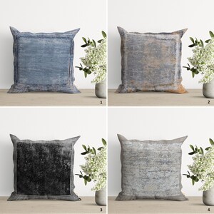 Op de afbeelding: Vier decoratieve kussens met verschillende patronen en kleuren. De kussens zijn allemaal vierkant en hebben een subtiele verweerde look. De kussens zijn gerangschikt in een rasterpatroon op een houten oppervlak.