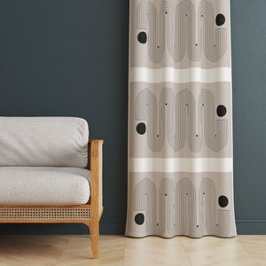 Pode incluir: Um par de cortinas bege com um padr&atilde;o geom&eacute;trico de arcos e c&iacute;rculos pretos. As cortinas est&atilde;o penduradas em uma parede azul escura.
