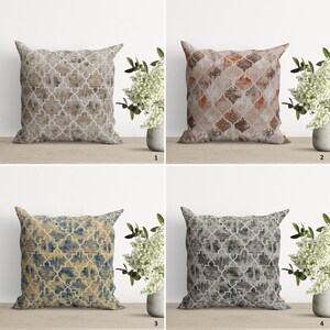 Op de afbeelding: Vier decoratieve kussens met een geometrisch patroon in verschillende kleuren, waaronder beige, bruin, blauw en grijs. De kussens zijn gerangschikt in een raster op een houten oppervlak.