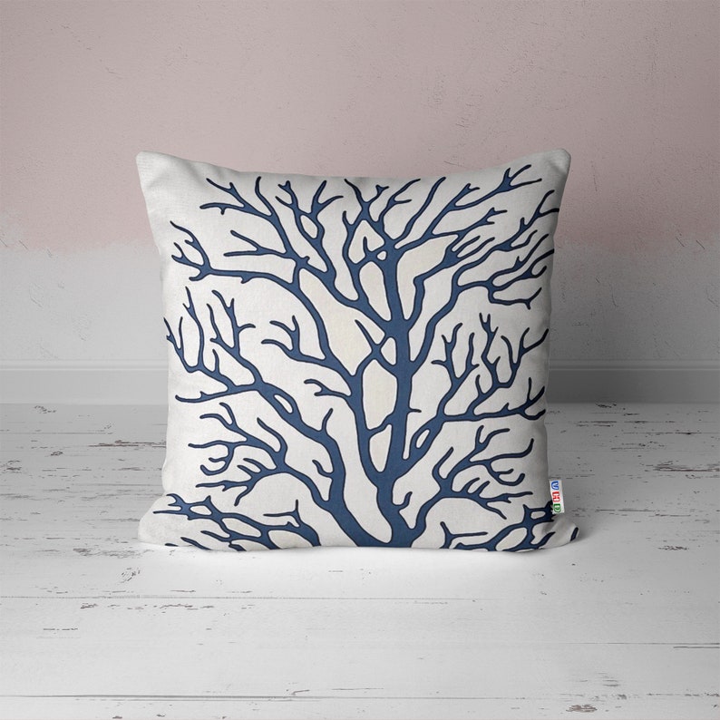A white throw pillow with a navy blue coral branch design.