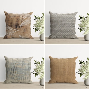 Op de afbeelding: Vier verschillende decoratieve kussenhoezen met verschillende patronen. De kussens zijn gerangschikt in een raster op een houten oppervlak. De kussens zijn allemaal vierkant en hebben een neutrale kleurenpalet. De patronen omvatten een houtnerfpatroon, een geometrisch patroon, een blauw en wit abstract patroon en een linnenstructuur.