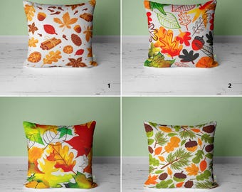 May include: Four different pillow designs featuring autumn leaves in various colors and patterns. The pillows are white with a variety of fall foliage, including red, orange, yellow, and green leaves.