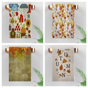 May include: Four different kitchen towels with autumn themes. The first towel has a colorful illustration of fall leaves, pumpkins, and other fall-themed items. The second towel has a pattern of orange and yellow leaves on a white background. The third towel has a close-up of fall leaves on a brown background. The fourth towel has a white background with the word "AUTUMN" spelled out in black letters with fall-themed illustrations.