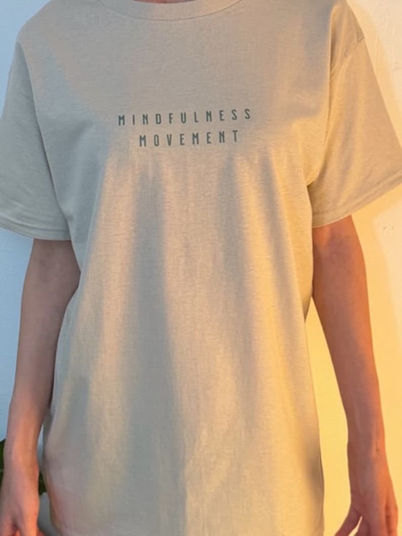 May include: A light beige t-shirt with the text "MINDFULNESS MOVEMENT" printed on the front.