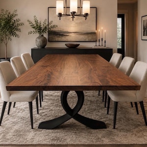 May include: A rectangular dining table with a thick, natural-toned wood grain top and a black metal base featuring a curved, intersecting design. Six upholstered chairs with light beige fabric and black legs are arranged around the table.
