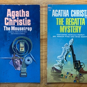 Könnte beinhalten: Zwei Vintage-Taschenbücher von Agatha Christie. "The Mousetrap" hat ein blaues Cover mit einer Collage von Bildern. "The Regatta Mystery" hat ein blau-gelbes Cover mit einer Revolver-Illustration. Beide Bücher sind von Dell.