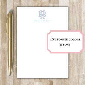 Può includere: Una penna dorata è appoggiata accanto a un foglio di carta intestata bianca personalizzata. La cancelleria presenta un monogramma azzurro e il nome "Bailey Miller". Un'etichetta rosa recita "Customize Colors & Font".