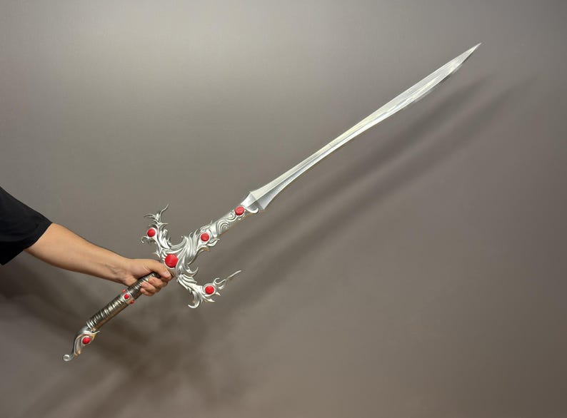 May include: A silver sword with a decorative handle and red gems. The sword has a long, straight blade and a pointed tip.