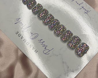 Op de afbeelding: Een set van tien vierkante press-on nagels bedekt met iriserende, veelkleurige strass-steentjes. De nagels zijn gerangschikt op een witte kaart met een marmerpatroon, voorzien van de tekst "HANDMADE Press On Nails" en "Thank you for your order."