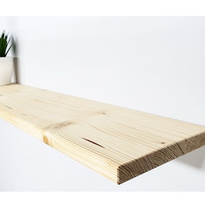 May include: A natural wood shelf with a smooth, light brown finish. The shelf is made of solid wood and has a slightly rounded edge.