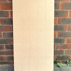K&ouml;nnte beinhalten: Eine hellbraune Holzt&uuml;r f&uuml;r einen Schrank mit vertikalem Paneeldesign. Die T&uuml;r ist aus mitteldichter Faserplatte (MDF) gefertigt und hat eine glatte, unbehandelte Oberfl&auml;che.