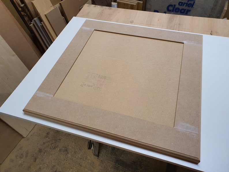 K&ouml;nnte beinhalten: Ein hellbrauner Holzrahmen mit wei&szlig;em Hintergrund. Der Rahmen besteht aus zwei Holzst&uuml;cken, die an den Ecken zusammengef&uuml;gt sind. Der Rahmen ist etwa 46 cm breit und 61 cm lang.
