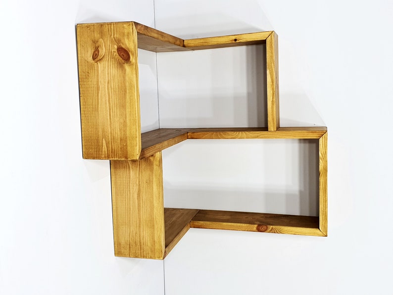 May include: A wooden corner shelf unit with three shelves. The shelves are made of natural wood with a light brown stain.