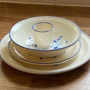 May include: A set of three white ceramic bowls with blue floral designs. The bowls are nested inside each other, with the largest bowl on the bottom and the smallest bowl on top. The bowls have a blue rim.