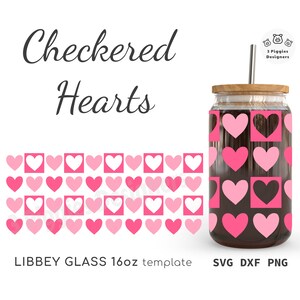 Op de afbeelding: Een glazen beker met een houten deksel en een metalen rietje. De beker heeft een ontwerp van roze harten in een dambordpatroon. De woorden "Checkered Hearts" zijn geschreven in een scriptlettertype. De beker is een 473ml Libbey glastemplate.