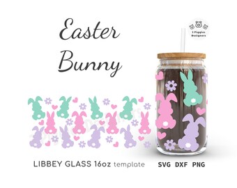 Puede incluir: Un tarro de vidrio transparente con tapa de madera y pajita, decorado con siluetas de conejitos de Pascua en colores pastel, flores y corazones. Las palabras "Easter Bunny" están escritas en una fuente cursiva. El tarro es un diseño de 473 ml.