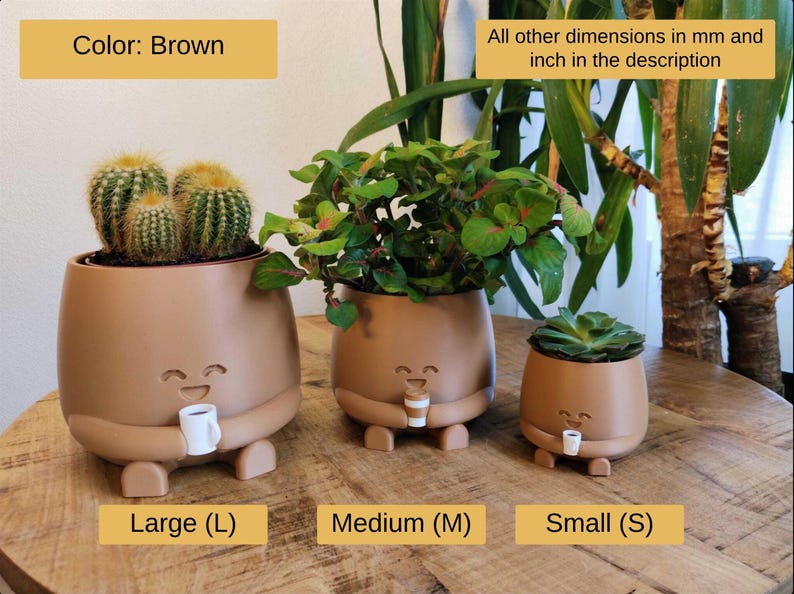 May include: Three brown ceramic plant pots of different sizes, each with a smiling face and holding a small cup. The largest pot contains cacti, the medium one has green plants, and the smallest has a succulent. Measurements in cm are in the description.